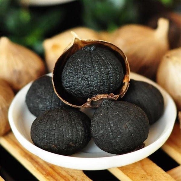 Holland black garlic vegetable in a 0.15 kg pack, showing dark, roasted garlic bulbs with a textured appearance.