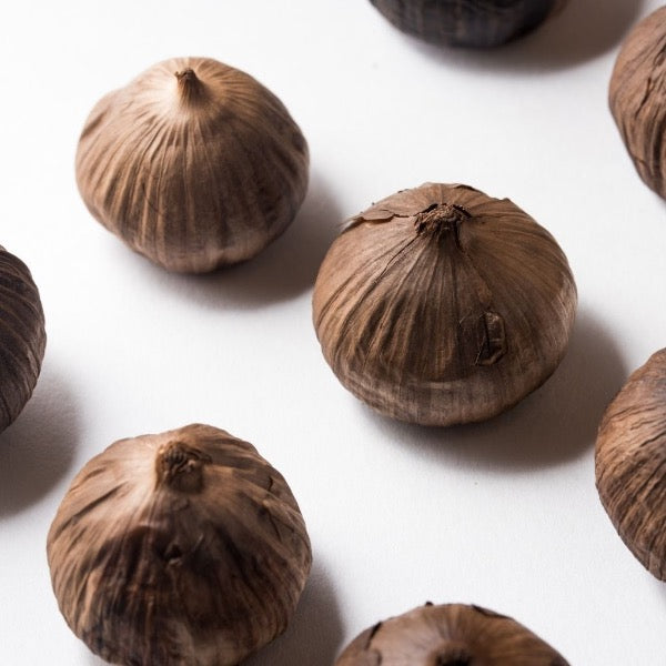 Black garlic vegetable from Holland in a 0.15 kg pack, showing glossy, dark cloves with a smooth surface.