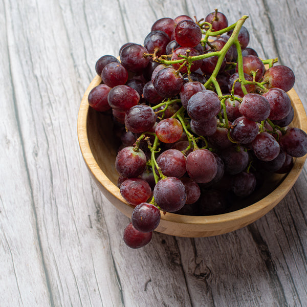 Red seedless grapes from Sharbatly in a 1 kg pack, showing fresh, vibrant grapes with green stems and juicy appearance.